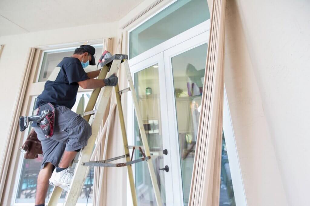 A man installing hurricane panels on his home